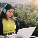 young-girl-in-headphones-sitting-on-park-bench-wor-2025-03-12-21-27-16-utc